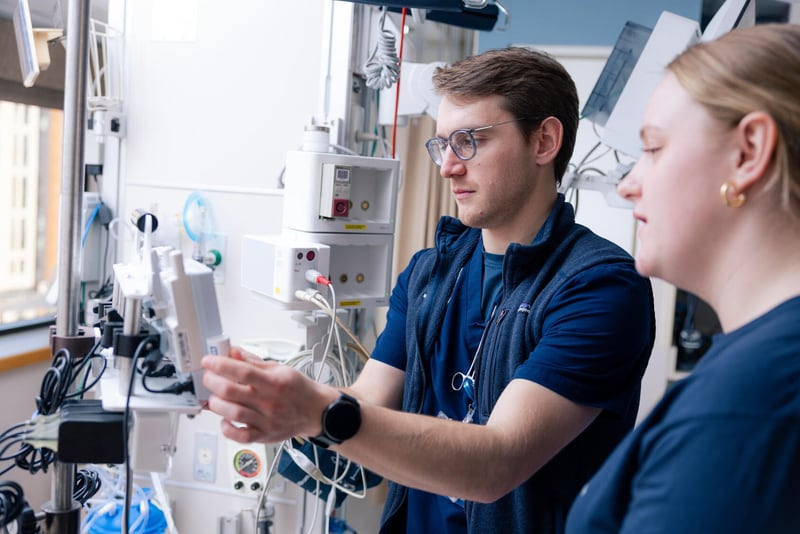 Dos enfermeras de Mayo Clinic trabajan juntas utilizando equipo médico en una habitación de hospital.